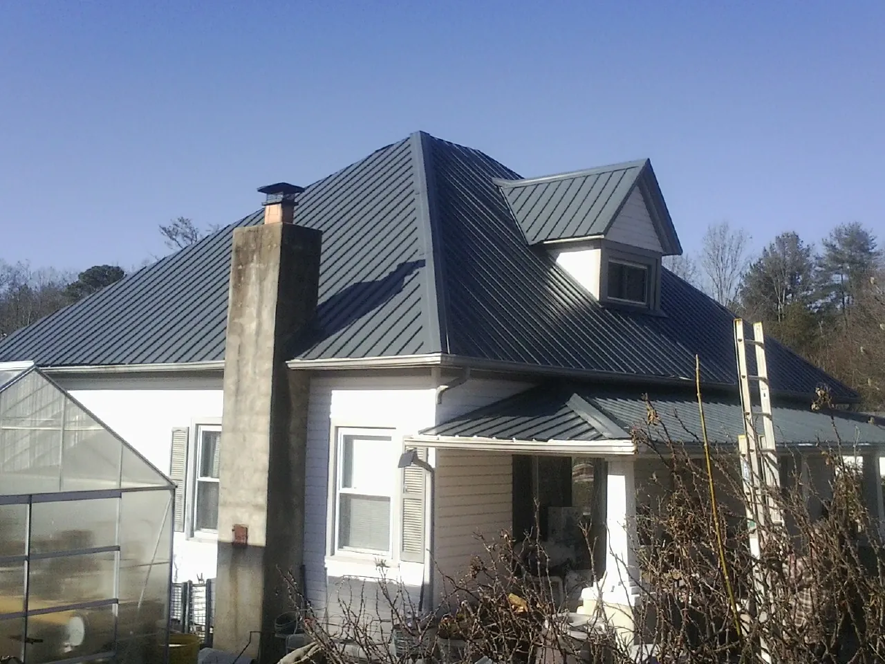 Dark blue standing seam metal roof on a white farmhouse with dormer — Slate & Tile Roof Repair by Roofing Brothers in Moores Hill
