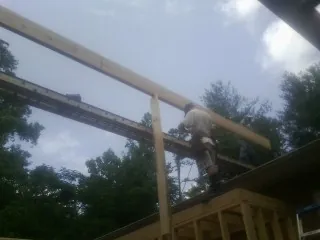 Carpenter setting a ridge beam over a new addition frame — Ice Dam Removal by Roofing Brothers in Moores Hill
