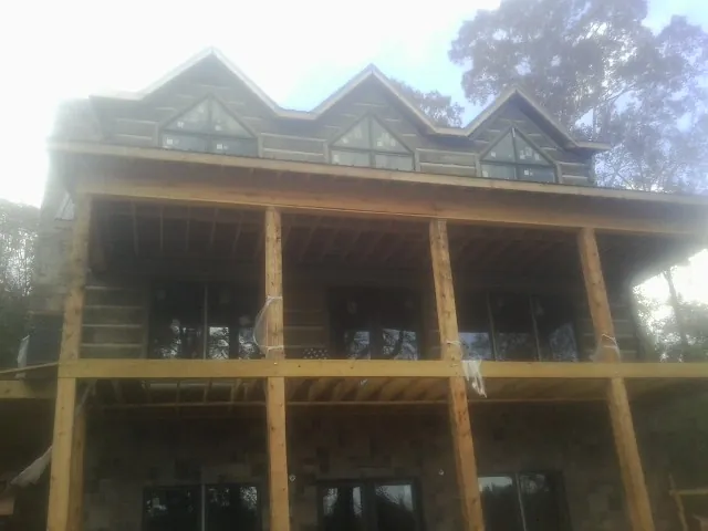 Dormers and porch framing on a large log home under construction — Roof Coating work by our crew in Moores Hill