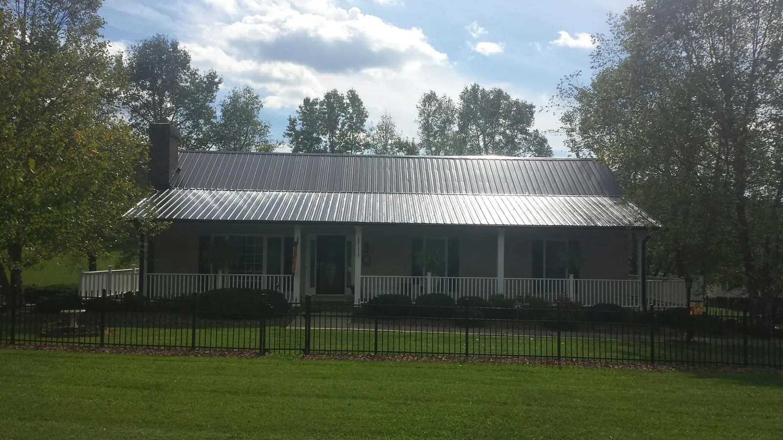 Gray metal roof on a brick ranch with a full width front porch — Gutter Guard Installation work by our crew in Moores Hill
