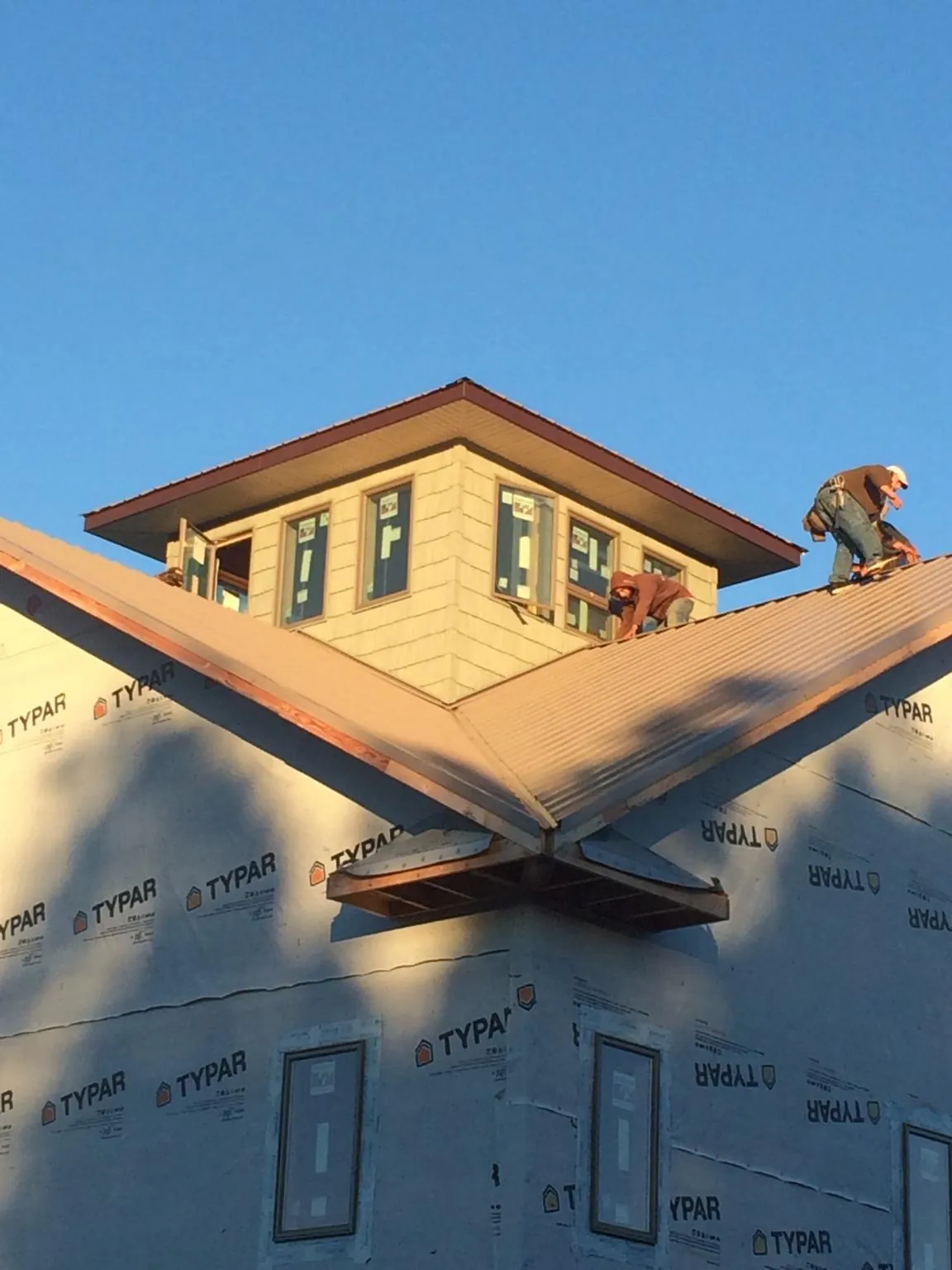 Roofers working around a rooftop cupola on a new metal roof at sunset — Roof Waterproofing in Moores Hill by Roofing Brothers